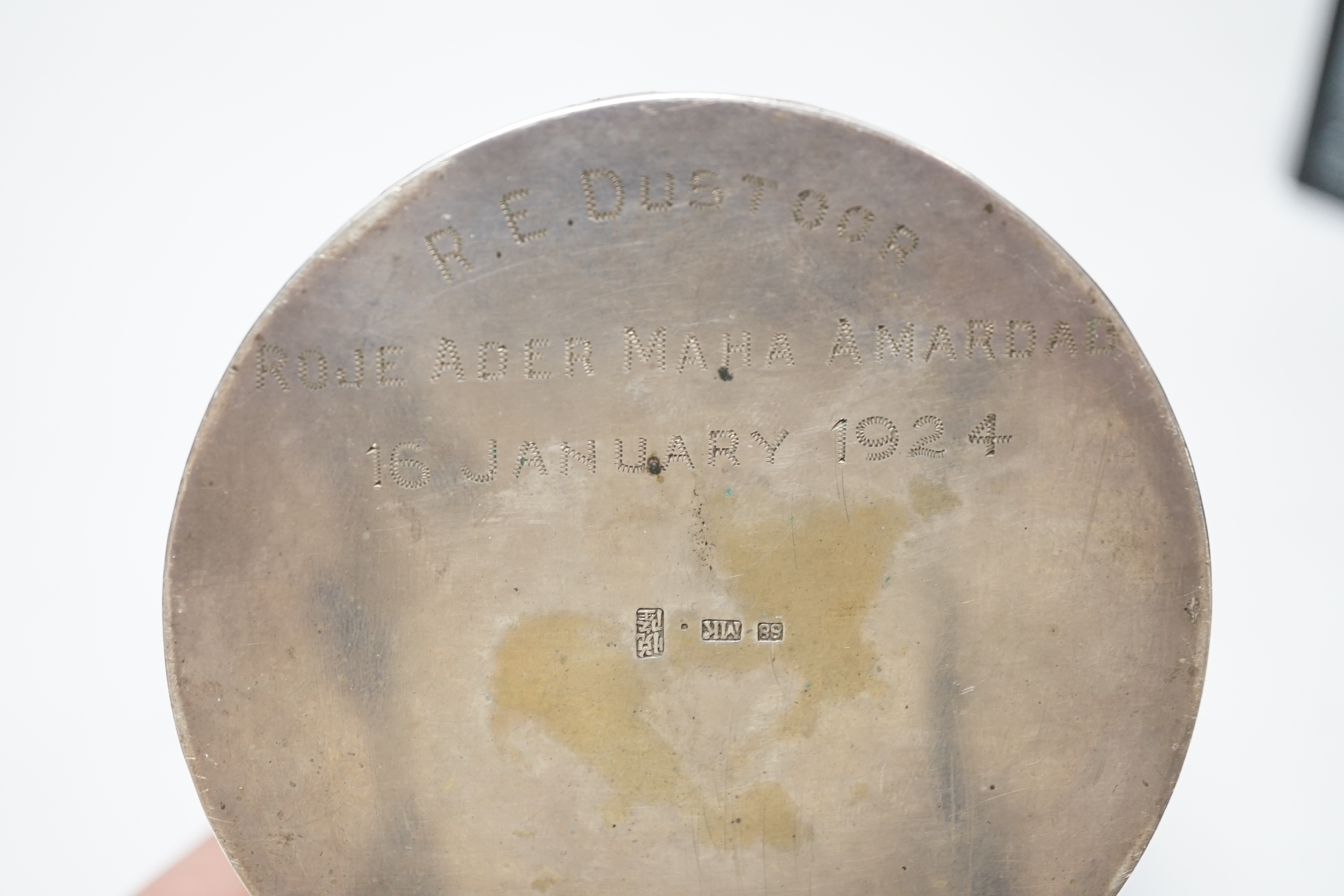 An early 20th century Chinese white metal circular box and cover, maker's mark MK, with foliate decoration and engraved inscription, diameter 82mm, 128 grams.